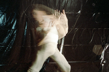long exposure of a young Ahasiw dancing against a black tarp